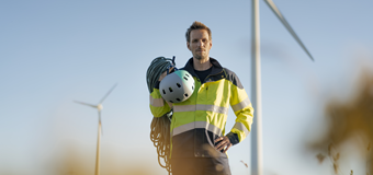 An engineer stands in front of wind turbines